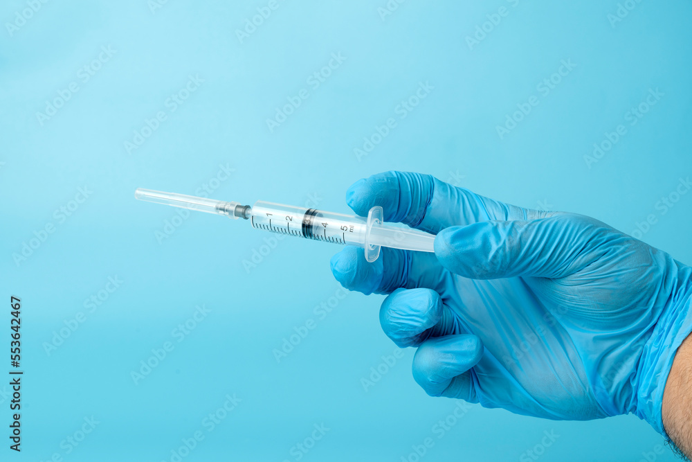 syringe in the doctor's hand on a blue background syringe in the doctor's hand on a blue background