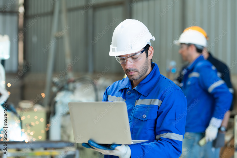 Group of engineers are manipulating a welding robot hand. By combining welding manipulation with a control panel Group of engineers are manipulating a welding robot hand. By combining welding manipulation with a control panel