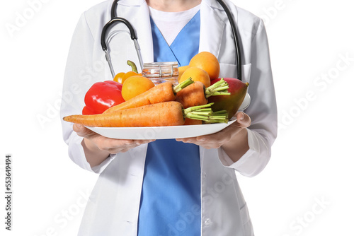 Female doctor with plate of vegetables on white background