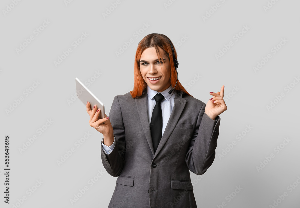 Beautiful transgender secretary in headset with tablet computer on grey background Beautiful transgender secretary in headset with tablet computer on grey background