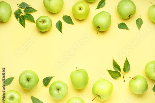 Composition with ripe green apples and leaves on yellow background