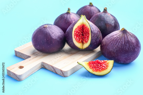 Wooden board with fresh ripe figs on color background, closeup