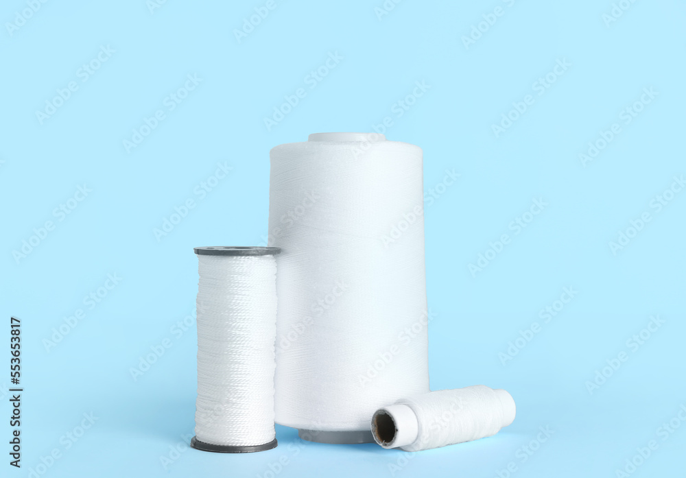 White thread spools on color background White thread spools on color background