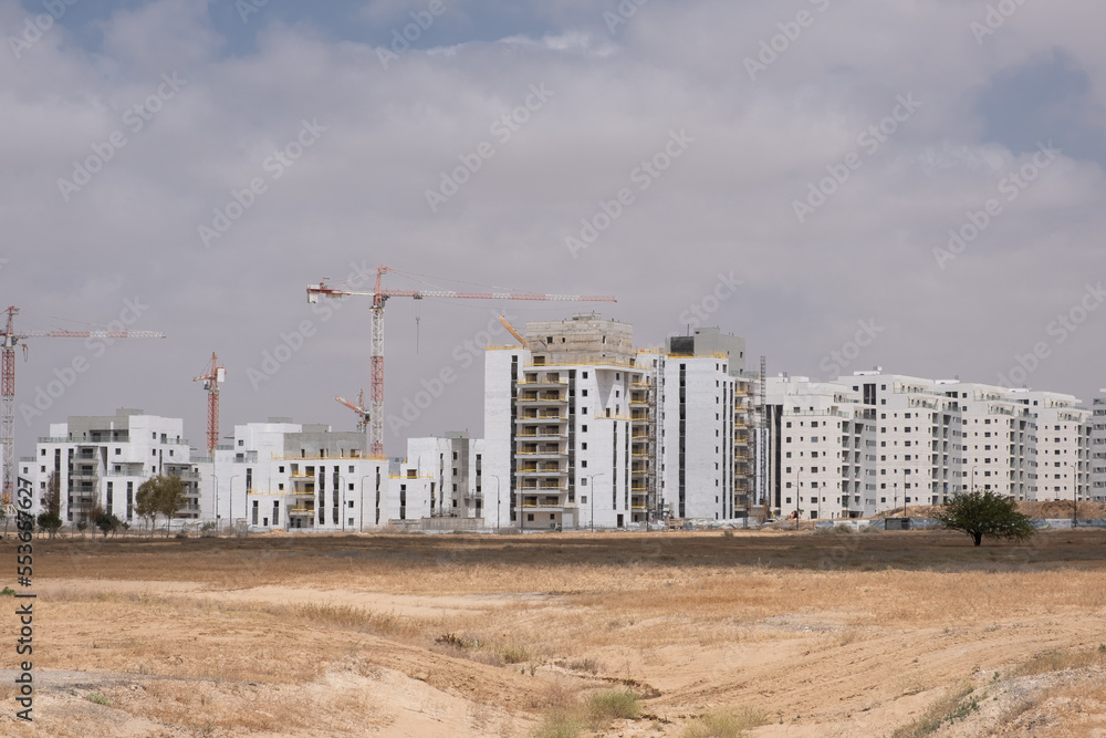 Development, new construction in the south district of Israel, new apartment buildings. Building a new site with heaps of ground in front.