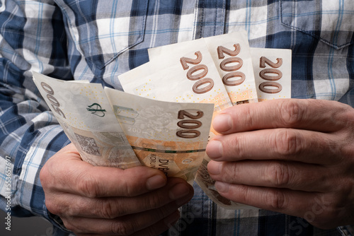 Counting Czech koruna in various nominal banknotes CZK. Hold a small cash money on hand. Czechia finance concept. Close up selective focus. photo