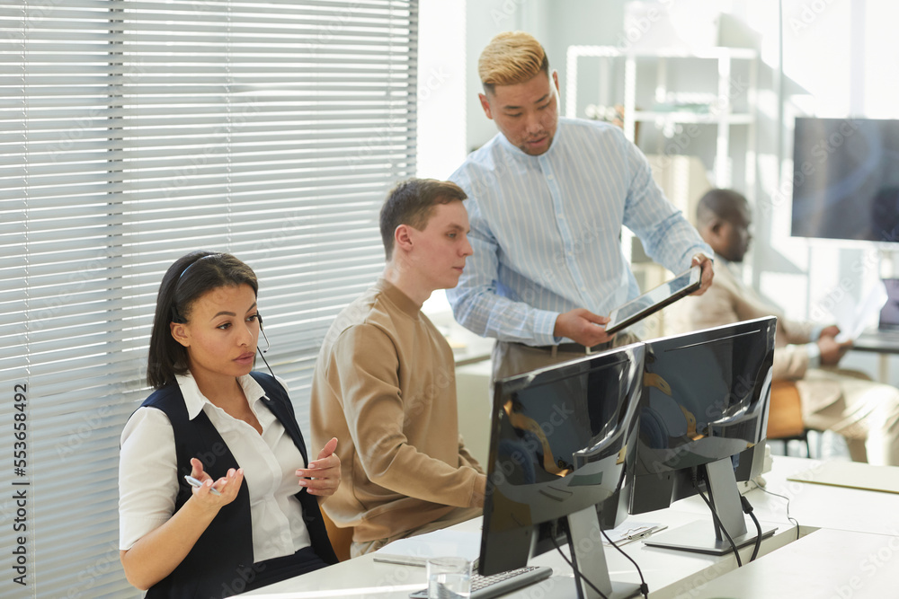 Diverse group of people working in call center focus on black young woman wearing headset and consulting client Diverse group of people working in call center focus on black young woman wearing headset and consulting client