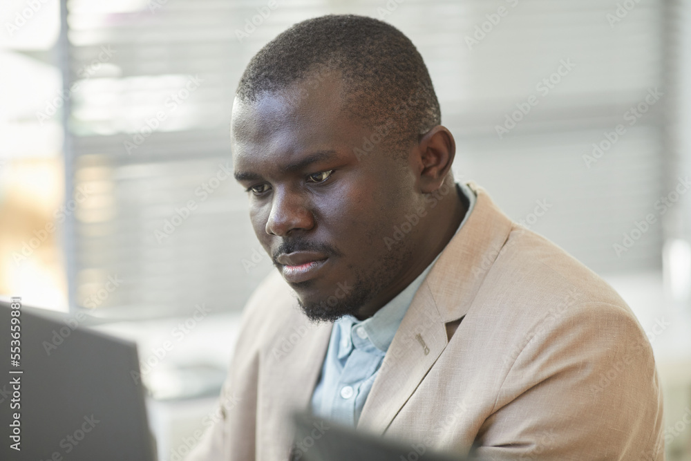 Close up of black man looking at computer screen while working in office cubicle Close up of black man looking at computer screen while working in office cubicle