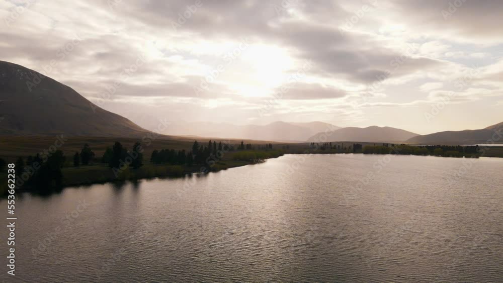 Hazy sunrise over golden mountains and a lake in New Zealand Hazy sunrise over golden mountains and a lake in New Zealand