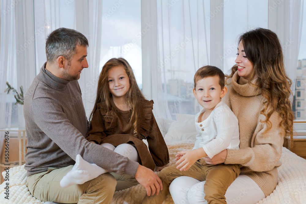 Happy family four spend time on bed hugging and smiling dad, mom and little kids bonding, loving caucasian parents, children unity, communication portrait