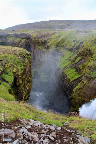 Majestic Icelandic Water fall with green moss and Lava rocks between cliff formation. damp fresh icelandic landscape with strong green and earth tones
