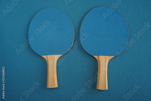 Two blue table tennis or ping pong rackets lie on a blue background with a close-up view from above. Game for leisure. Sport equipment. International competition. Table tennis. Healthy lifestyle
