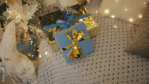 Packed Christmas presents, blue gifts boxes with golden yellow bows ribbons. New Year 2023 in Ukraine. National flag colors. Decorated tree, garland lights bokeh