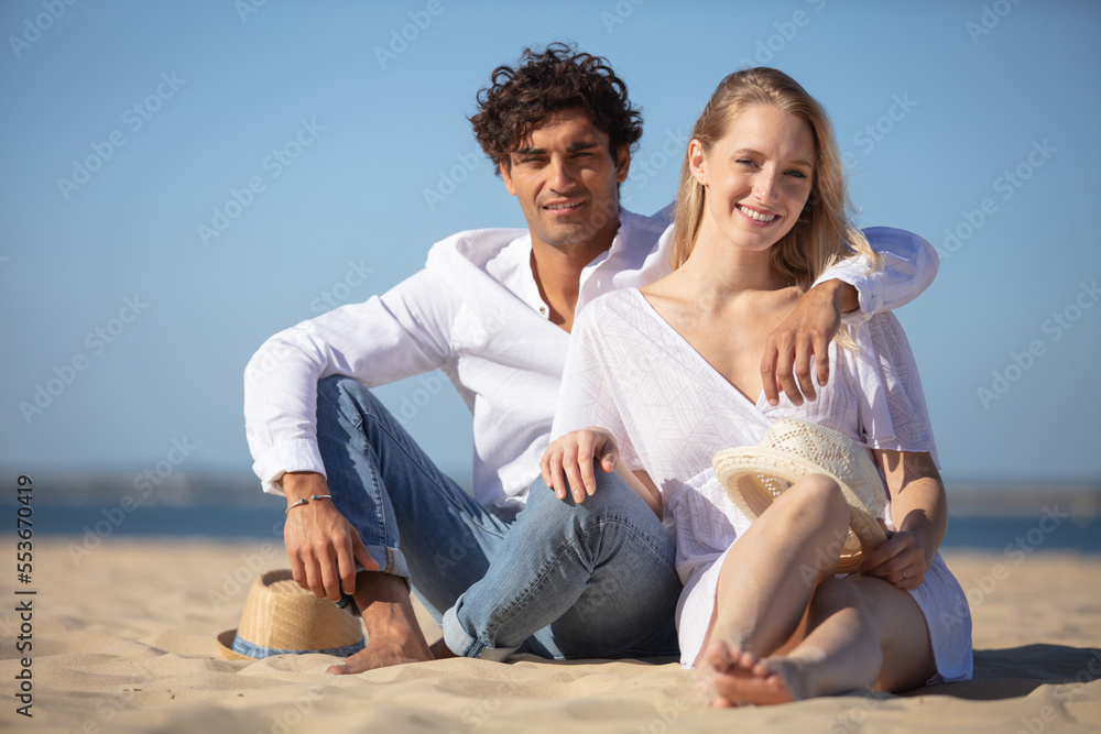 affectionate couple sit on the sand on the beach