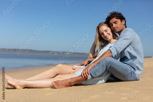 young healthy couple sited in the sand