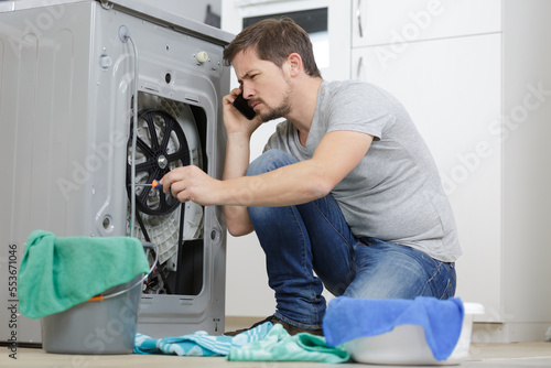 man calling plumber because of washing machine problems