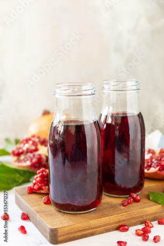 Pomegranate juice in glass bottles and fresh pomegranate fruits. Healthy drink diet immunity vitamins or vegetarian food concept. Copy space.