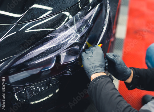 Bilde på lerret Two hands in protective black rubber gloves covering vehicle headlight with film to darken them