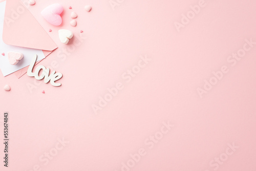 Valentine's Day concept. Top view photo of envelope with letter heart shaped marshmallow inscription love and sprinkles on isolated pastel pink background with copyspace © ActionGP