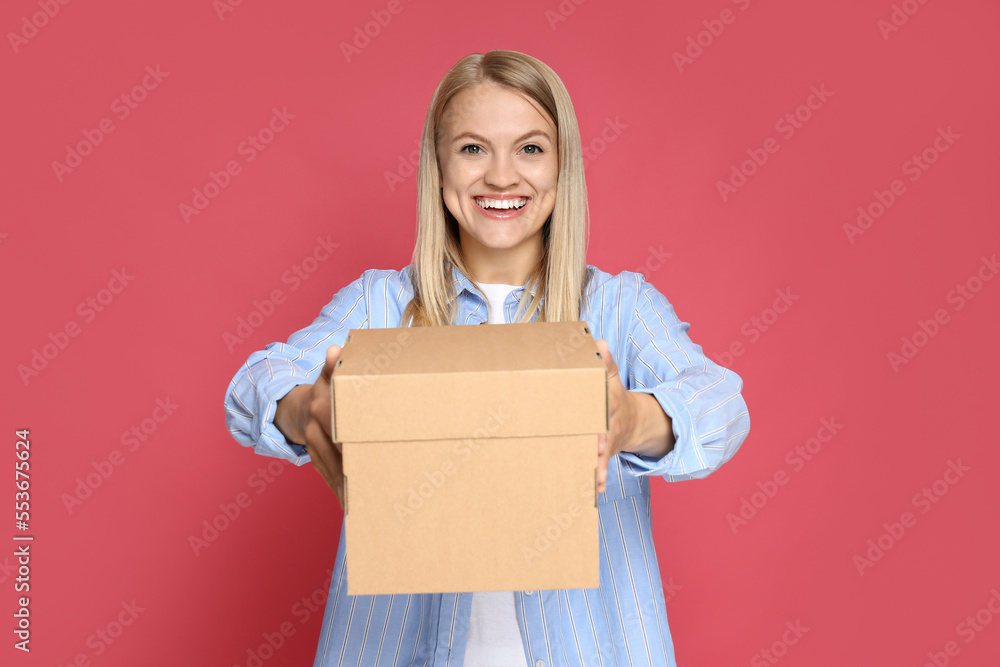 Concept of delivery and gift, young woman holds box on pink background Concept of delivery and gift, young woman holds box on pink background