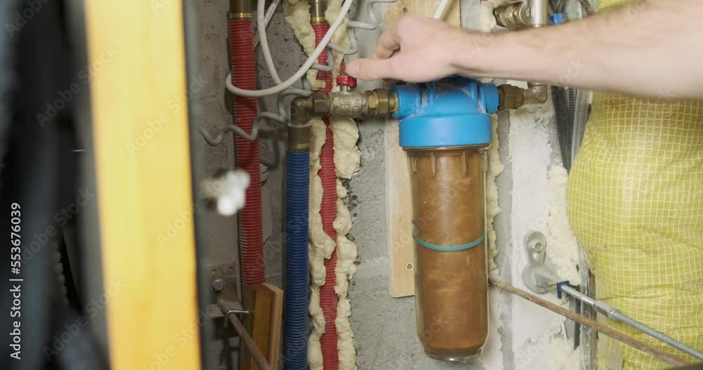 Plumbing cabinet, a man opens a water supply tap through a coarse filter. Plumbing cabinet, a man opens a water supply tap through a coarse filter.