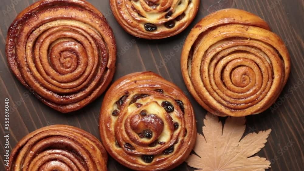 Homemade buns with cinnamon and raisins, spinning on a dark wooden background. Close-up Homemade buns with cinnamon and raisins, spinning on a dark wooden background. Close-up