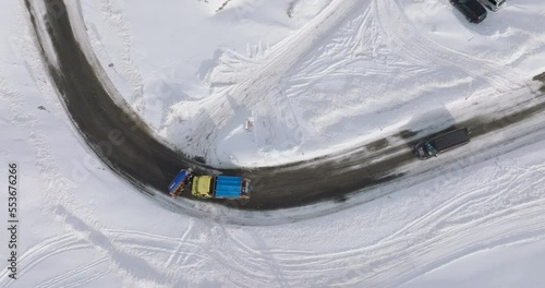 Street plow driving on road, top down view of snow covered landscape and snow plow passing on clear road in the Alps. photo