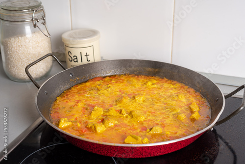 Pan for paellas with vegetables, ingredients and meat taking temperature, in the absence of adding the rice, close-up.