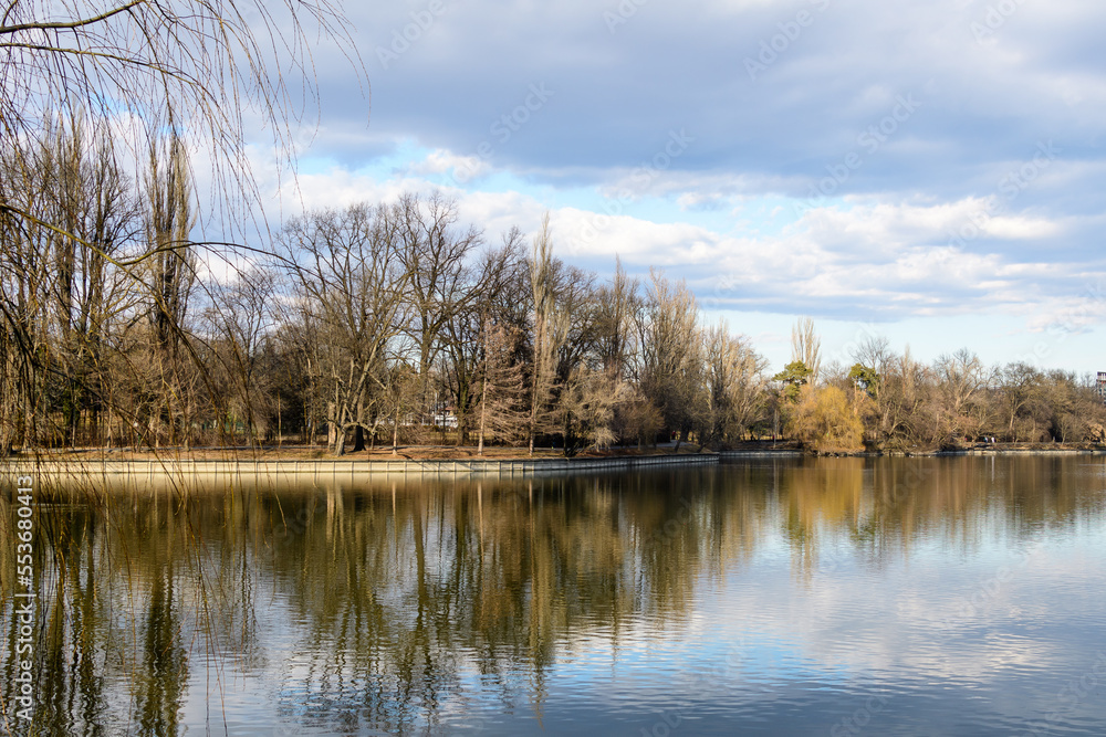 Landscape with large old trees near Herastrau lake in King Michael I Park (Herastrau) in Bucharest, Romania, in a sunny winter day Landscape with large old trees near Herastrau lake in King Michael I Park (Herastrau) in Bucharest, Romania, in a sunny winter day