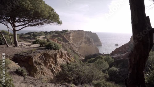 A man is flying his drone from a cliff in joao de arens beach in Portimao, Portugal photo