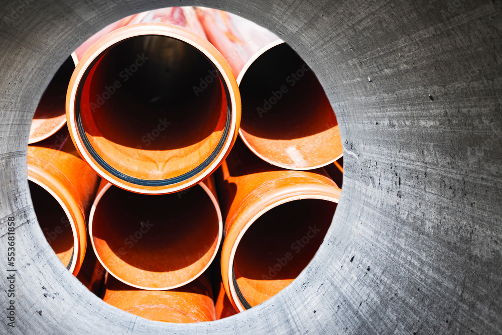 Orange sewer pipes close up. Underground pipeline works. Modern sewage disposal systems of the city. Water supply at home. View from the big pipe. Orange sewer pipes close up. Underground pipeline works. Modern sewage disposal systems of the city. Water supply at home. View from the big pipe.