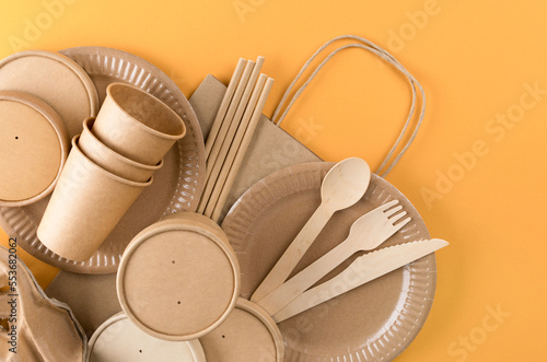 Paper utensils bundle, food packaging articles over orange background. Street food paper packaging, recyclable paperware, zero waste packaging concept. Flat lay style