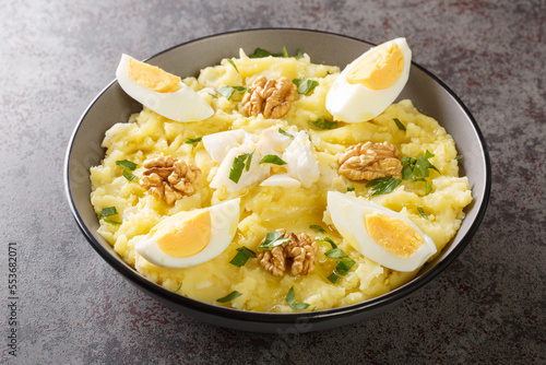 Obraz na plátne Delicious mashed potatoes with salted cod and garlic served with walnuts and boiled eggs close-up in a bowl on the table