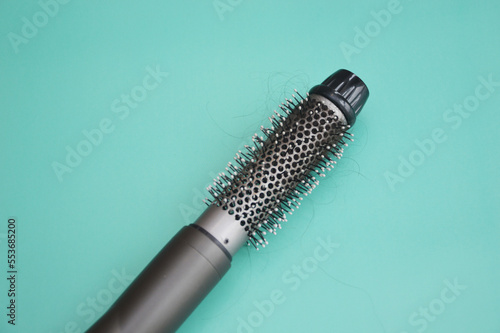 Electric hair dryer with a round brush. Coiled hair after drying. Hair loss. Rotating hair brush, styler, barber tool.