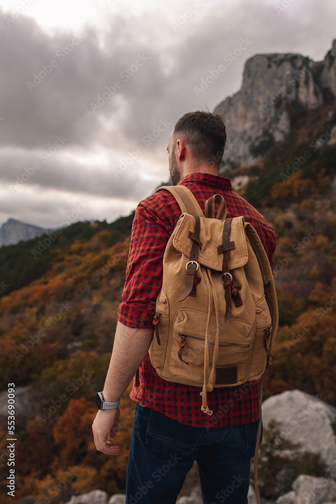 The traveler admires the beautiful view from the mountain.
Traveler, tourist in autumn landscape. Mountains and trekking. Concept: Adventure, Vacation, Travel.