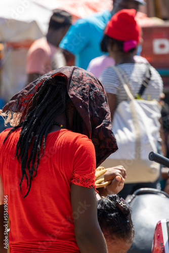 Scenes from the Haitian market near the border with Haiti. Unrecognizable Haitian woman from behind carrying with afro rasta hair looking at some goods in a vendor's stall.