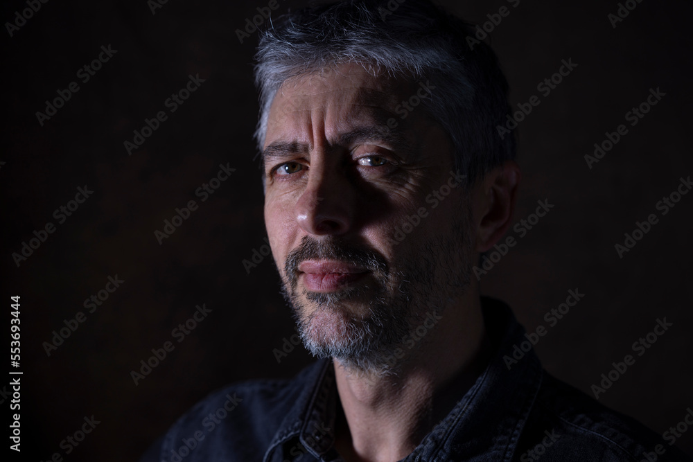 portrait d'un bel homme de 50 ans aux cheveux gris. Il sourit et regarde la caméra.