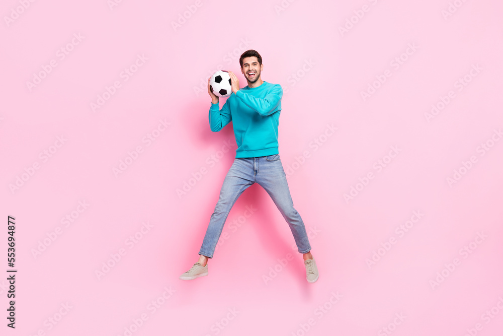 Full size photo of handsome young man jumping catch soccer ball goalkeeper dressed stylish blue clothes isolated on pink color background