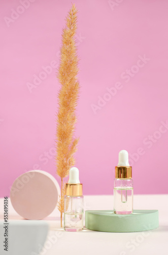 cosmetic bottle on a round plaster podium and pampas grass. Essential oil or serum