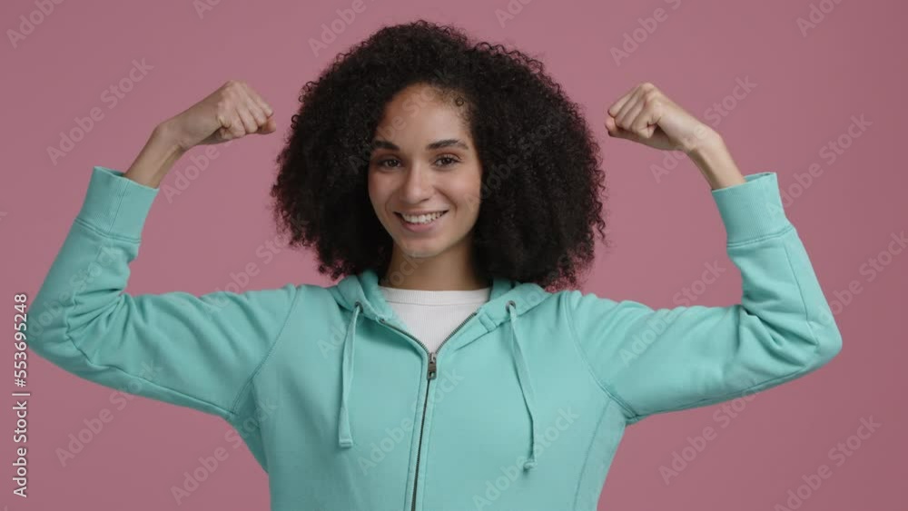 Portrait of a healthy, sporty female after workout. Woman with curly hair showing her biceps and smiling. High quality 4k footage Portrait of a healthy, sporty female after workout. Woman with curly hair showing her biceps and smiling. High quality 4k footage