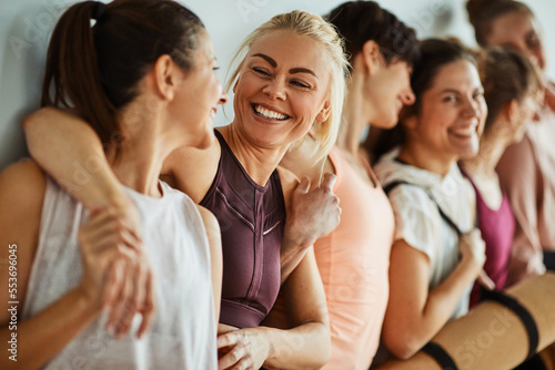 Laughing friends standing together at the gym after yoga class photo