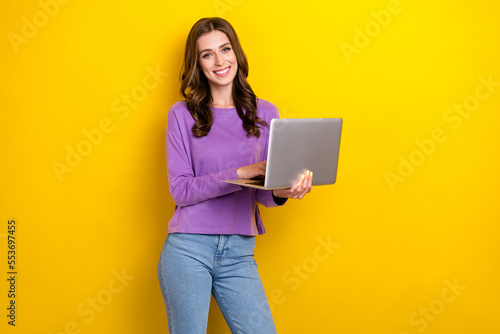 Photo of positive nice girl toothy smile hold use wireless netbook isolated on yellow color background