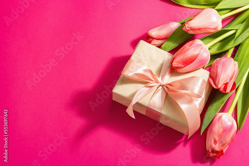 Greeting concept flower composition, a bouquet of pink tulips, and a gift.