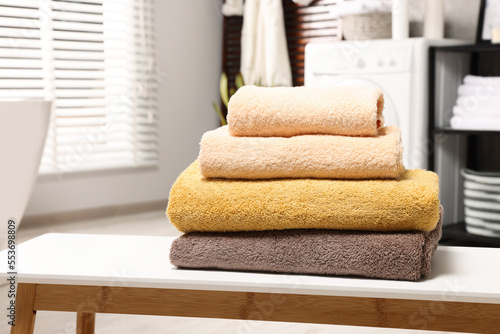 Stack of clean towels on white table in laundry room, space for text © New Africa