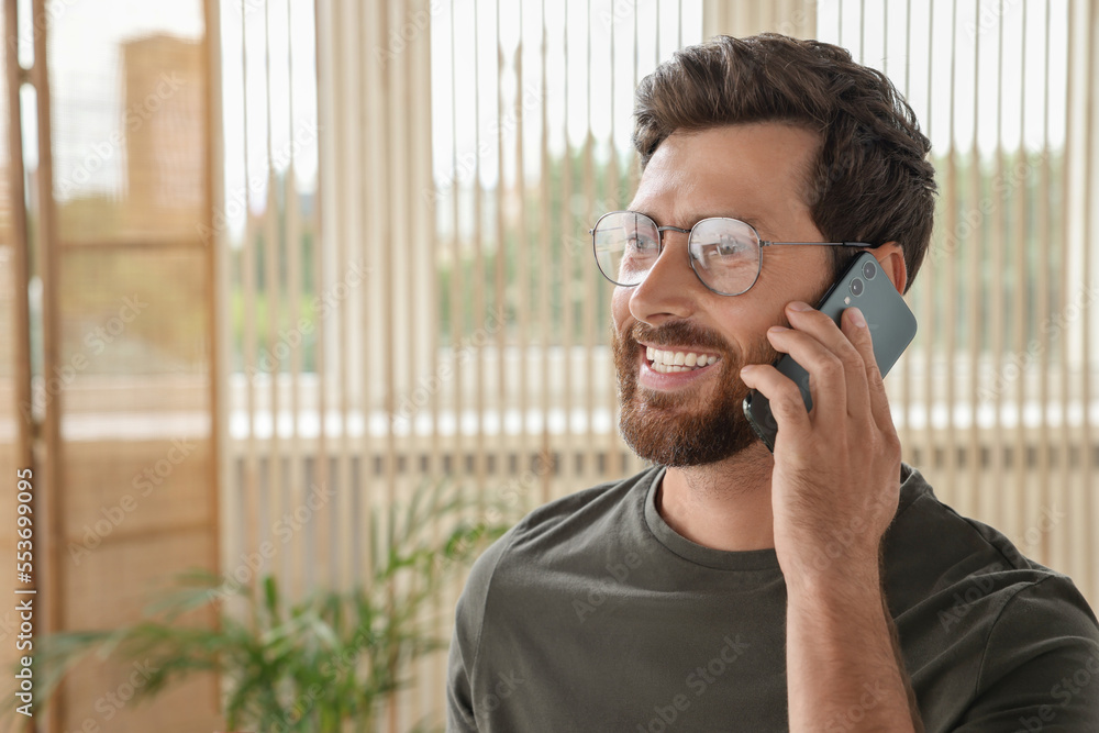 Handsome man talking on smartphone at home, space for text Handsome man talking on smartphone at home, space for text
