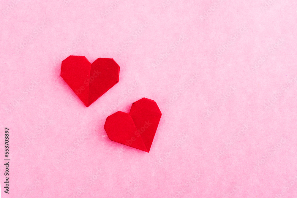 Red origami hearts on pink background
