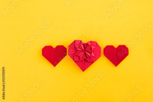 Red origami hearts on yellow background