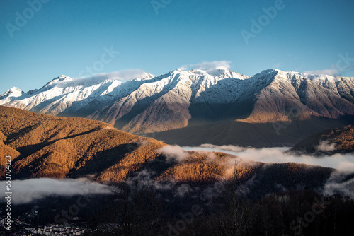 Landscape of nature from a chain of mountains covered with snow and forests at the foot