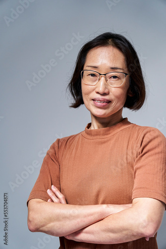 Mature Asian woman looking at the camera with arms crossed © PhotoAlto