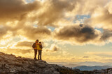 couple of mountaineers with backpacks hugging contemplating the sunset in the mountains while hiking. sport and outdoor adventure