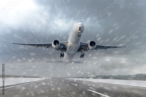 Fototapeta Naklejka Na Ścianę i Meble -  Take off of an airliner in heavy snow and a blizzard at the airport of departure. The concept of bad weather, flight delays and cancellations.
